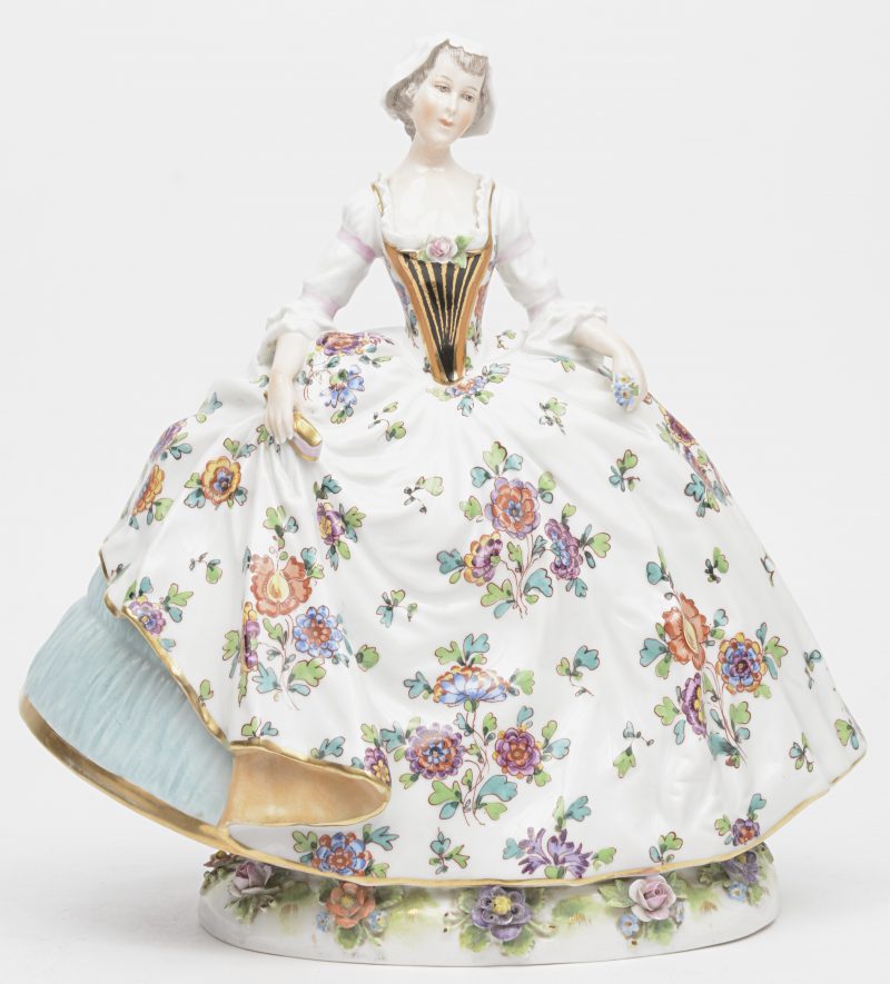 “Dame in bloemenjurk”. Een meerkleurig Duits porseleinen beeld. Gemerkt met gekroonde N.