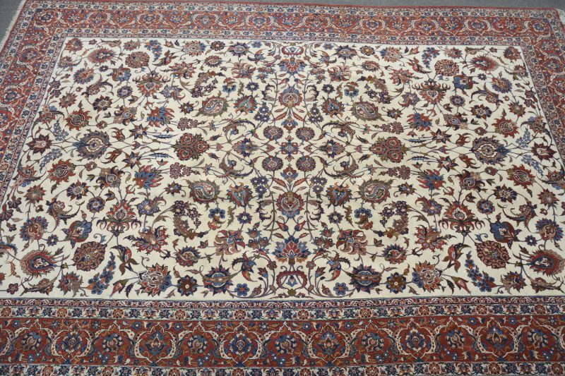 Een handgeknoopt Perzisch wollen karpet met decor van bloemen.