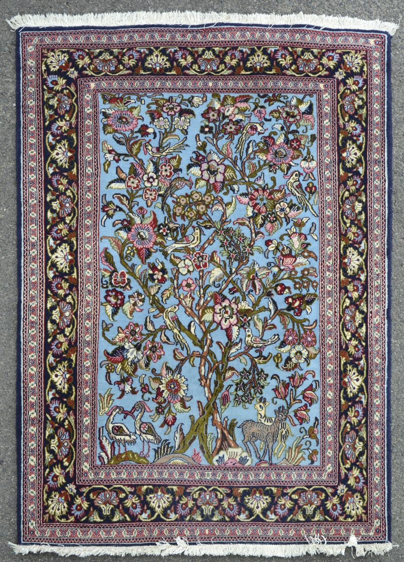 Een handgeknoopt Perzisch wollen kleedje met een bloeiende struik met vogels in het decor.