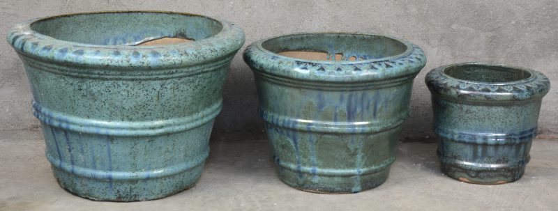 Drie aardewerken jardinières van blauw geglazuurd aardewerk in verschillende groottes.