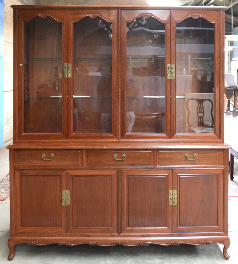 Een Chinees houten vitrinekast met twee dubbele deuren en glazen leggers en met vier paneeldeuren en drie laden onderaan.