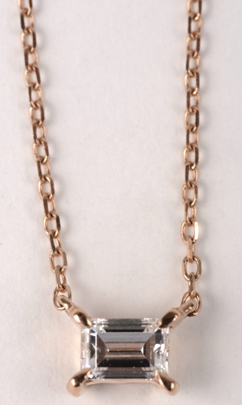 Een 18 K roze gouden ketting met hanger bezet met één diamant baguet van +- 0,22 ct.