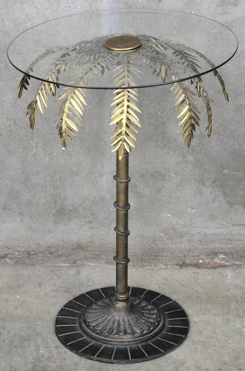 Een rond glazen tafeltje met een voet in de vorm van een palmboom.