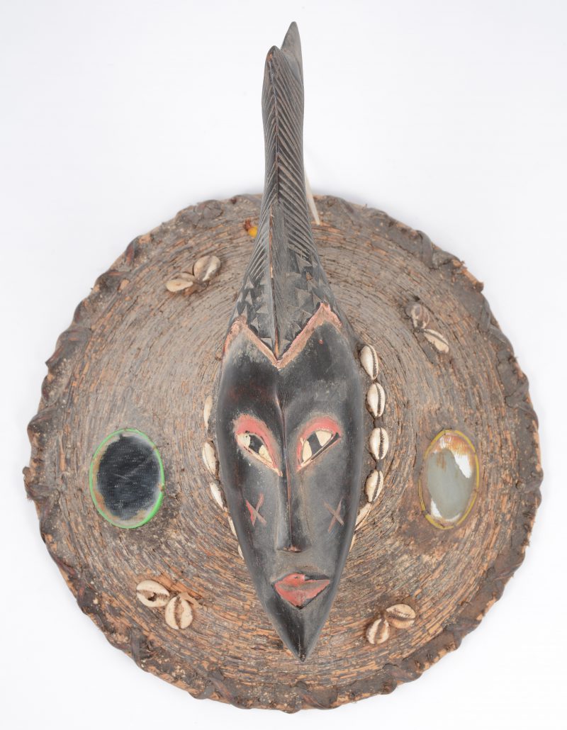 Een Afrikaans houten masker met vlechtwerk, spiegeltjes en schelpjes.