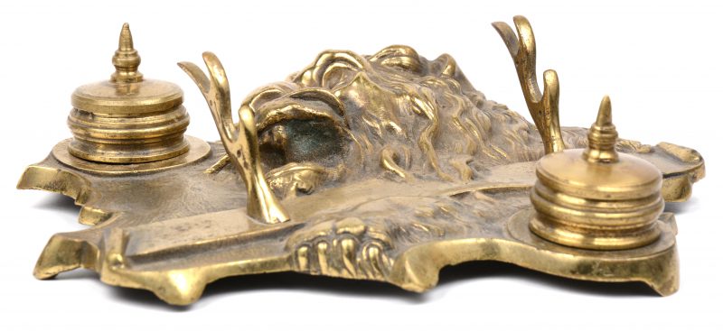 Een verguld bronzen inkstel met twee inktpotjes en een pennenhouder en versierd met leeuwenkop in reliëf.