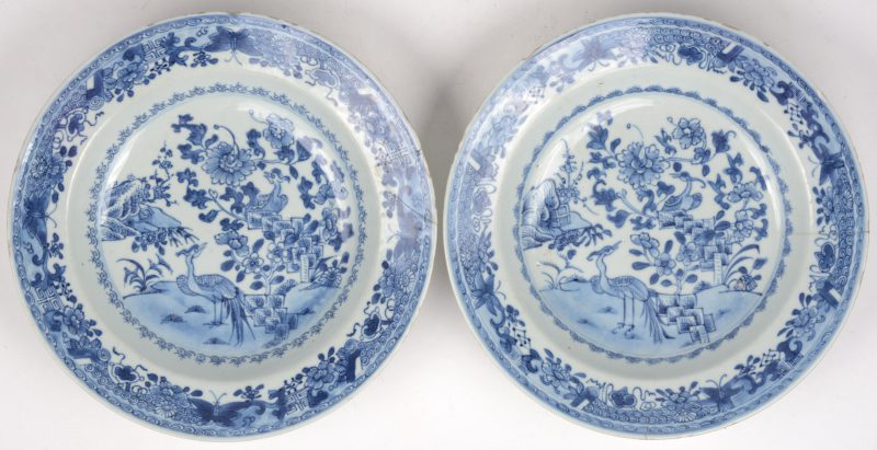 Een paar diepe borden van Chinees porselein met blauw op witte decors van vogels in een landschap. Eind XVIIIe eeuw. Een met herstelling, de andere met haarscheur.