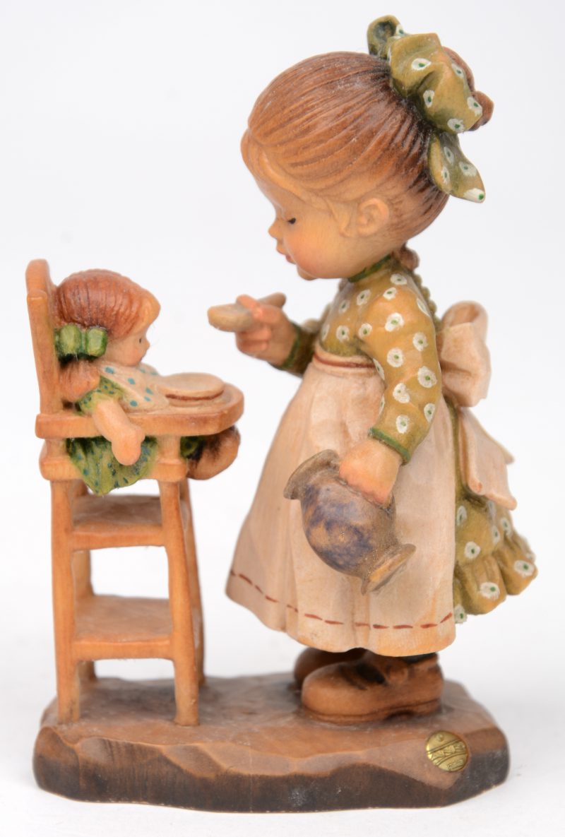 “Meisje met pop”. Een gepolychromeerd houten sculptuurtje.. Gemerkt en genummerd 1885/4000.