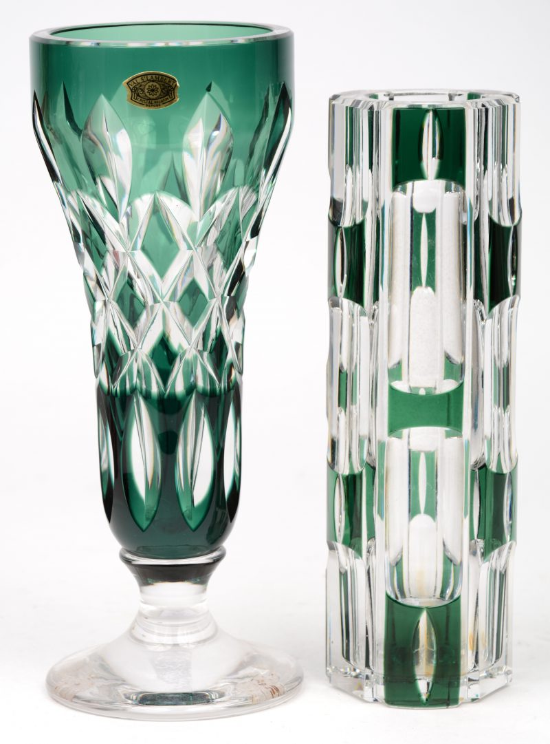 Een fluitvaasje op voet en een cilindervaasje van geslepen en groen gedubbel kristal. Beide gemerkt onderaan.