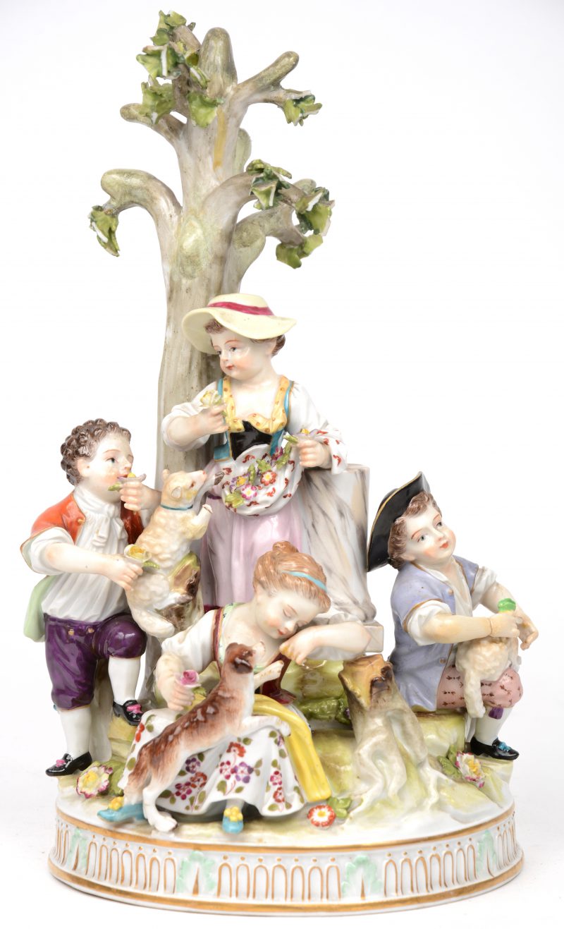Een grope van meerkleurig porselein met viif personages met lammetjes en een hondje. Gemerkt onderaan. Een pootje en een bloemblaadje en diverse blaadjes van het boompje manco, een handje gerestaureerd.
