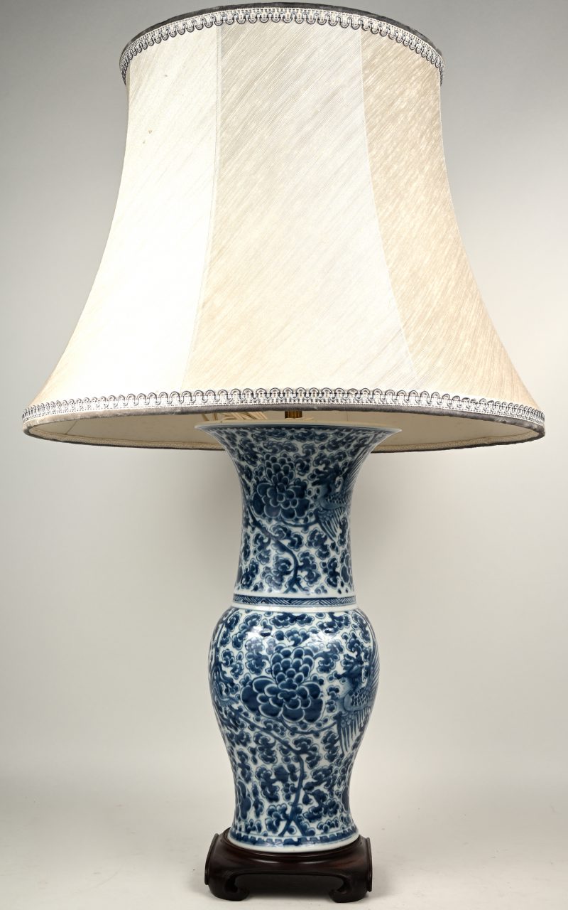 Een lampvoet van blauw en wit Chinees porselein met een decor van goudfazanten en pioenen. Op houten sokkel.