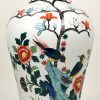 Een dekselvaasvormige lampvoet van porselein met een handgeschilderd meerkleurig decor van vogels en bloemen.
