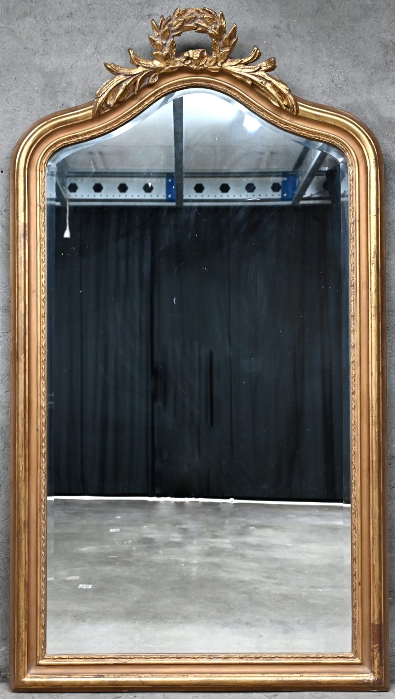 Een spiegel van verguld hout in lodewijk XV-stijl bovenaan versierd met een lauerkrans.