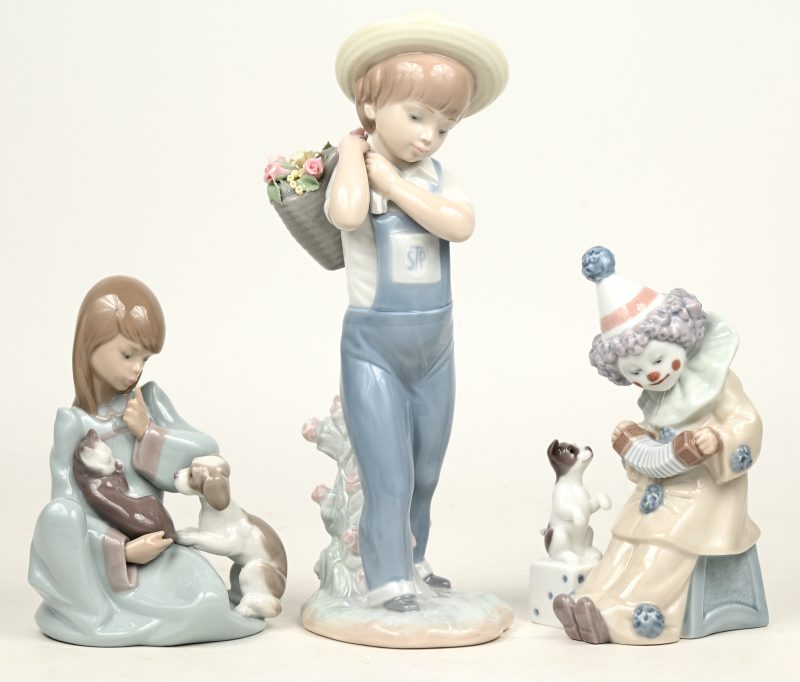 “Een jonge clown met hondje” ‘H. 15 cm), “Een meisje met kat en hond” (H. 13 cm) en “een bloemenjongen” (H. 24 cm). Drie beeldjes van gekleurd porselein. Onderaan gemerkt.