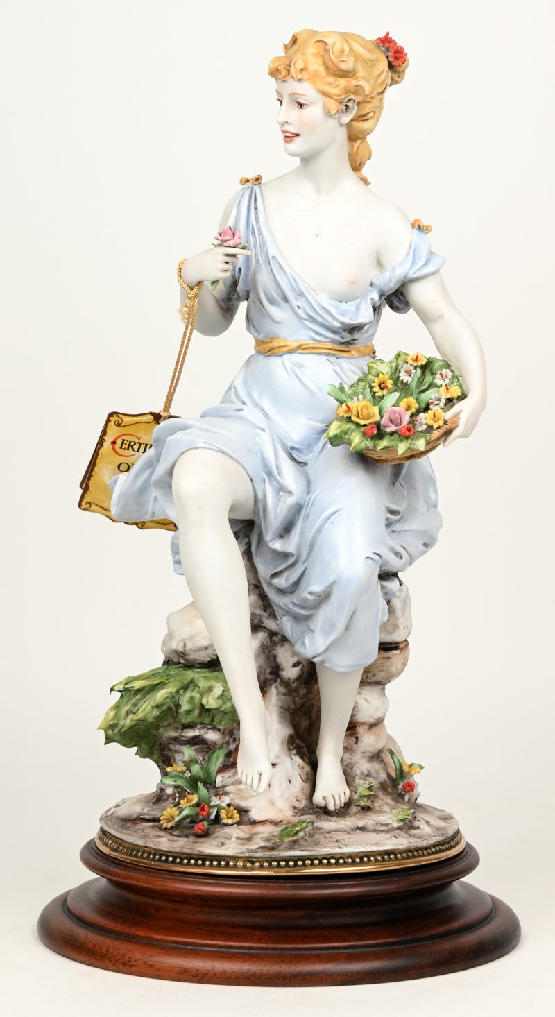 “Elegante dame met bloemen”. Groepje van gekleurd biscuit. Achteraan gemerkt en gesigneerd. Italiaans werk. Op houten sokkel.
