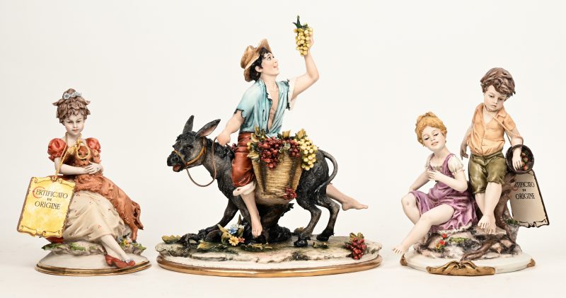 Drie beeldjes van gekleurd biscuit, waaronder een druivenoogster op een ezeltje (H. 24 cm). Italiaans werk. Achteraan gemerkt.