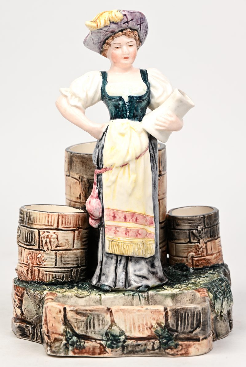 Een Italiaans aardewerken pennenhouder in de vorm van een vrouw met kruik bij drie waterputten. Eén scheurtje (bakfout).