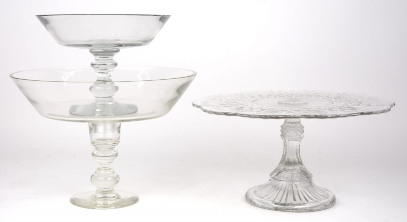 Een glazen fruitschaal op voet in twee delen en een taartschotel van gegoten  glas.