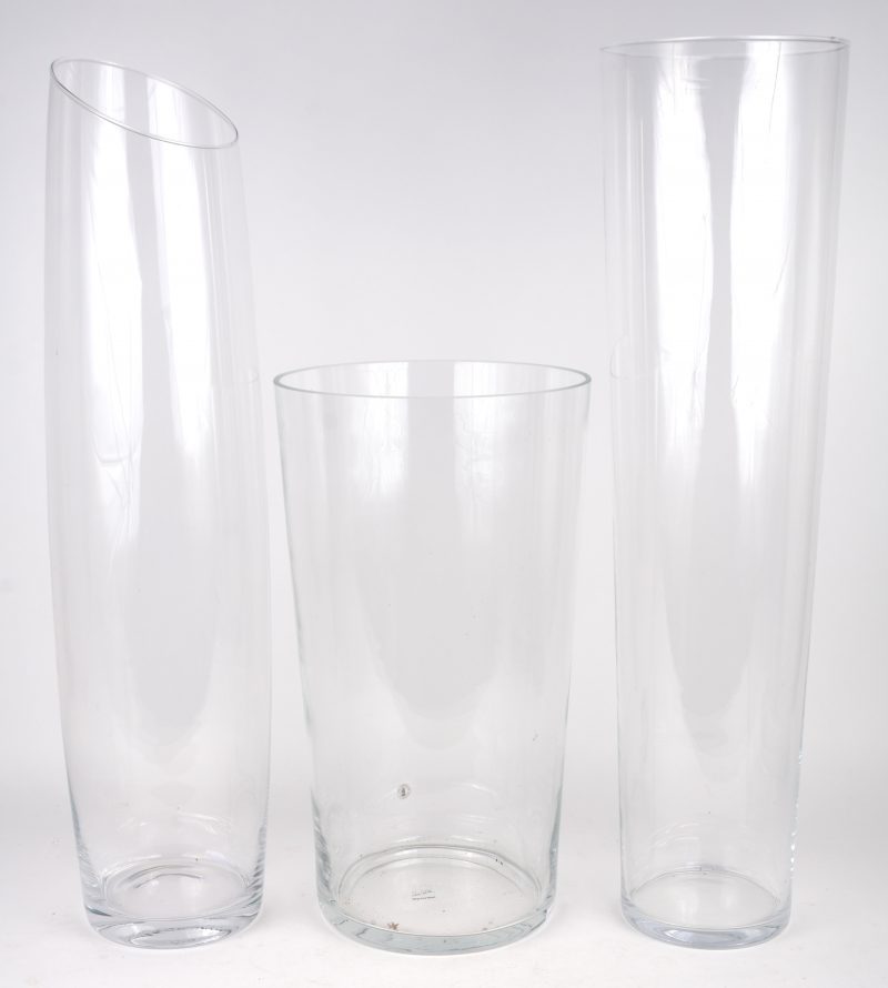Drie verschillende hoge vazen van kleurloos glas.