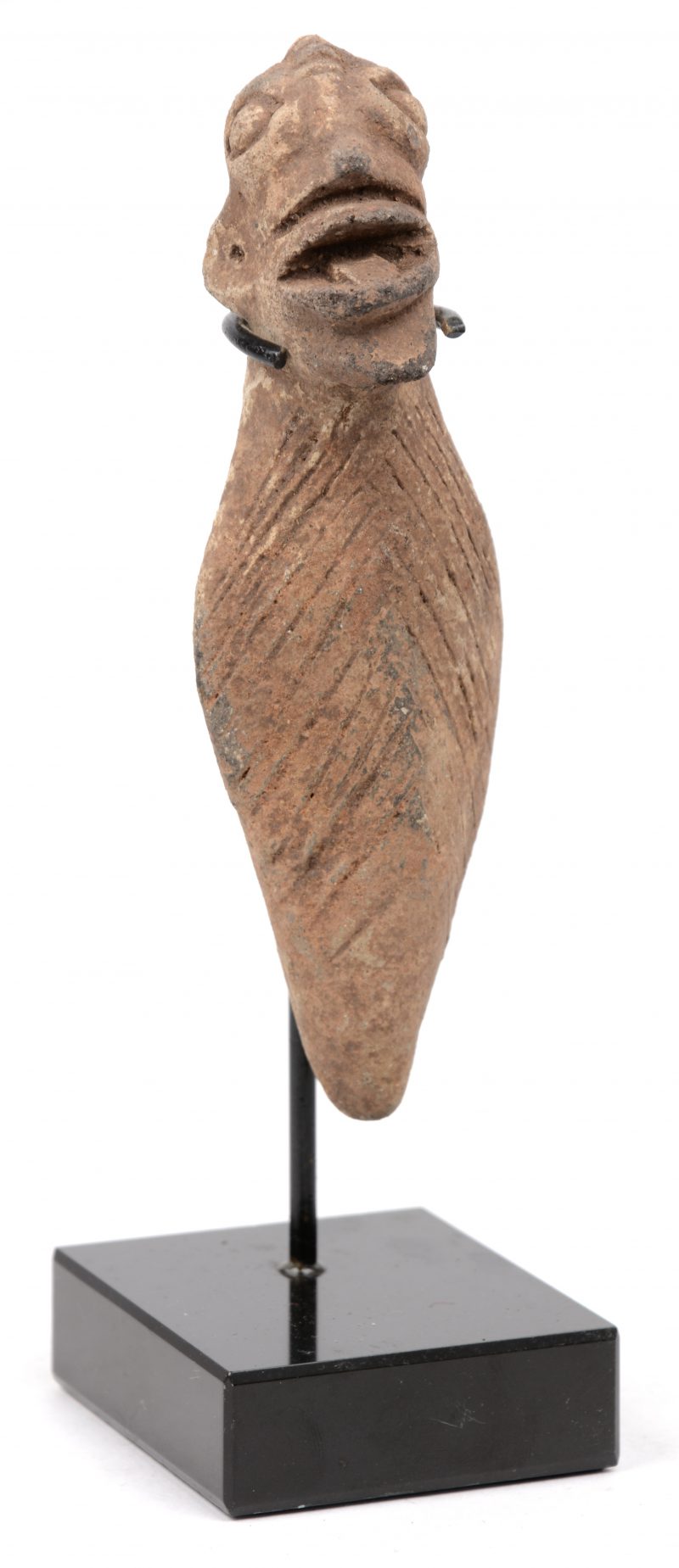 Een aardewerken beeldje met open mond en tong afkomstig uit het noorden van Ghana. 16e eeuws. Op een sokkel.