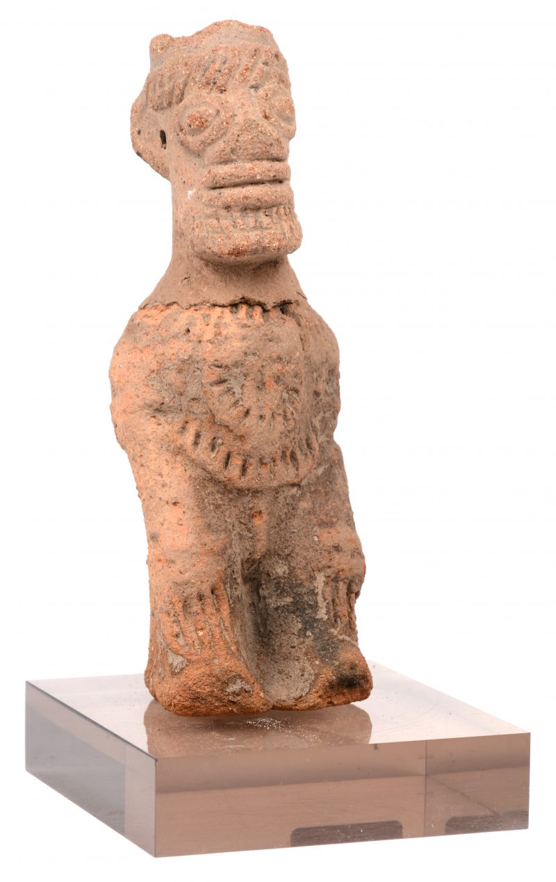 Een aardewerken beeldje van een zittende figuur afkomstig uit het noorden van Ghana. 16e eeuws. Restoratie aan de hals. Op een sokkel.