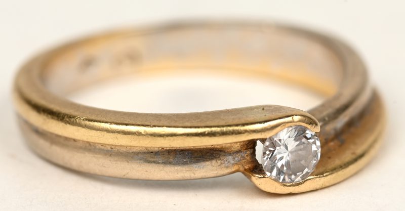 Een 18 K wit en geelgouden ring bezet met een briljant van +- 0,18 ct.
