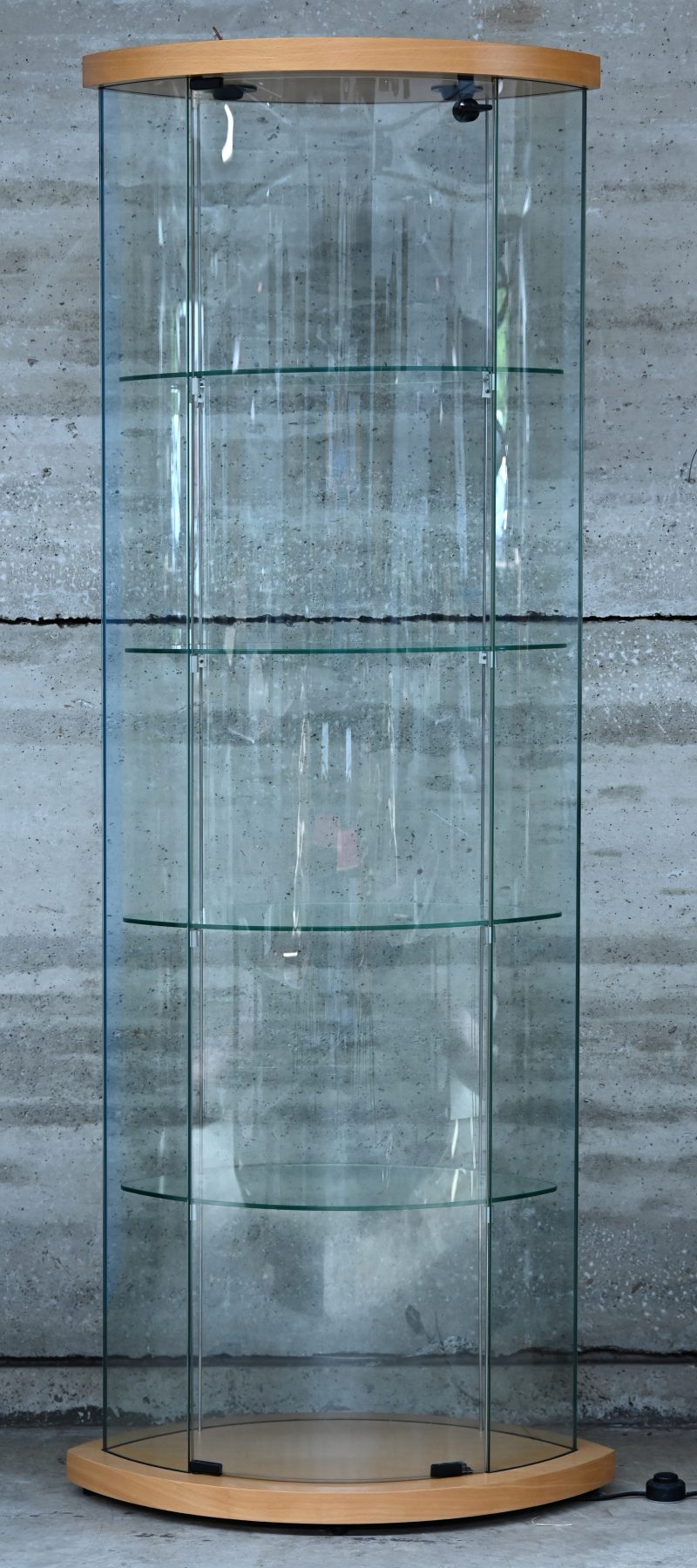 Een moderne vitrinekast met gebogen glazen en vier schappen.