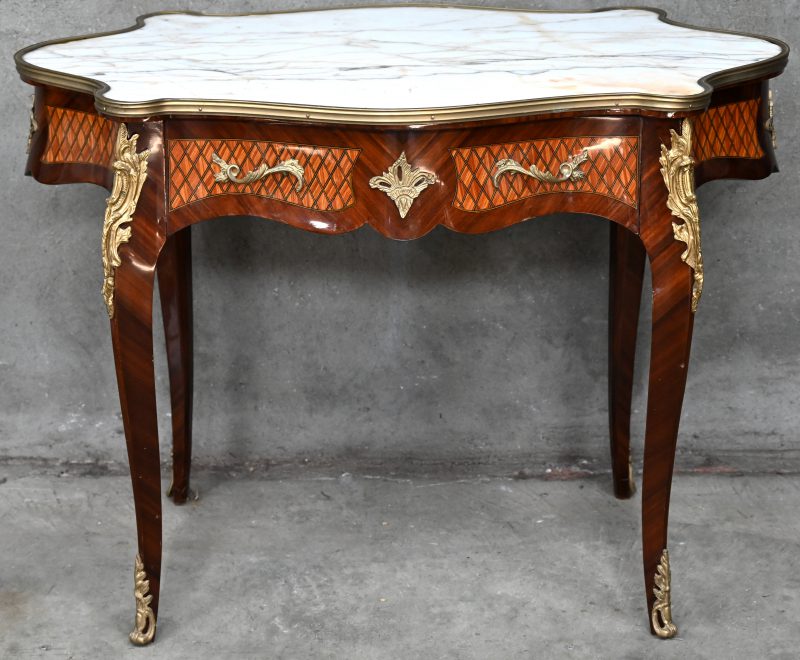 Een tafel in Lodewijk XV-stijl, met een lade, een marmeren blad en versierd met marqueterie.