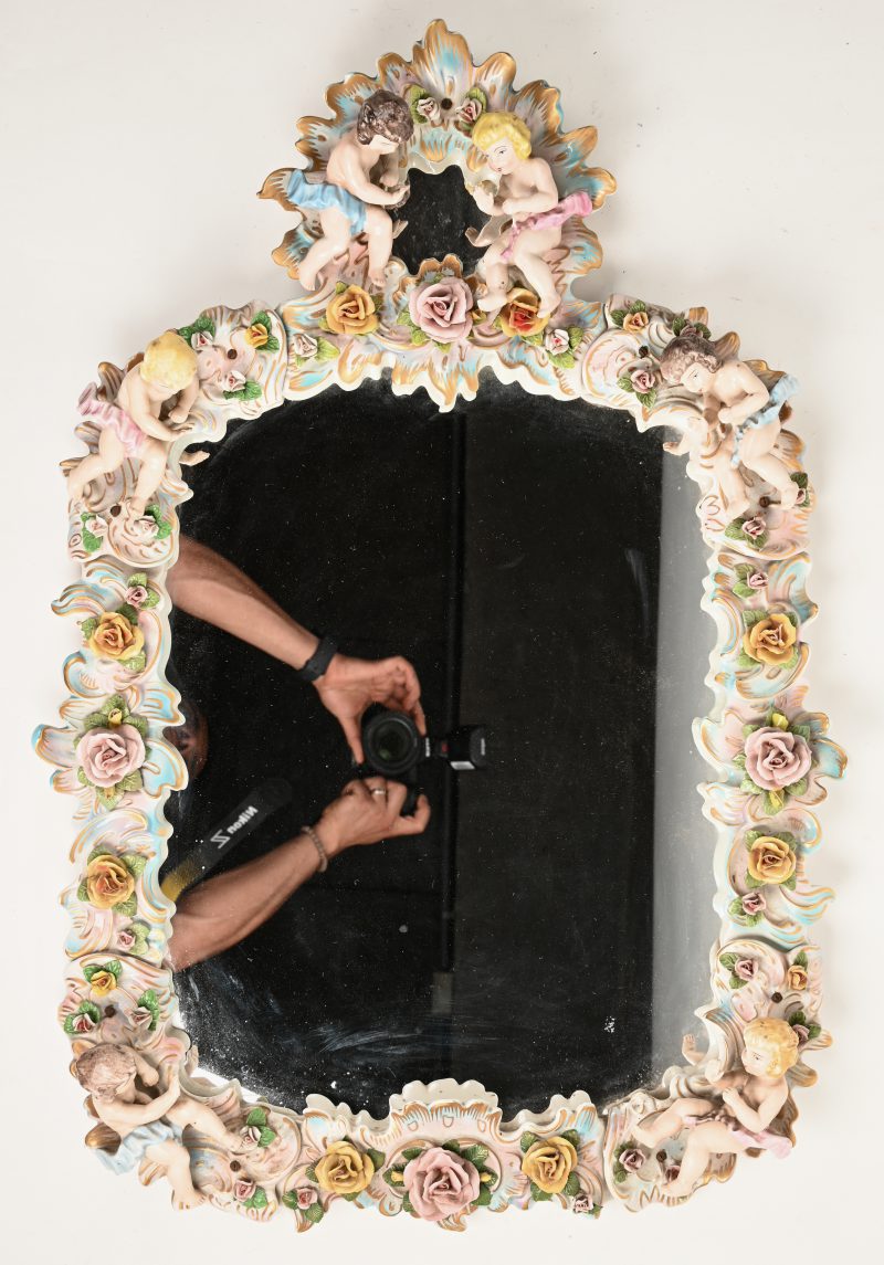 Een spiegel van Duits porselein. Uitbundieg versierd met engelen en bloemen.