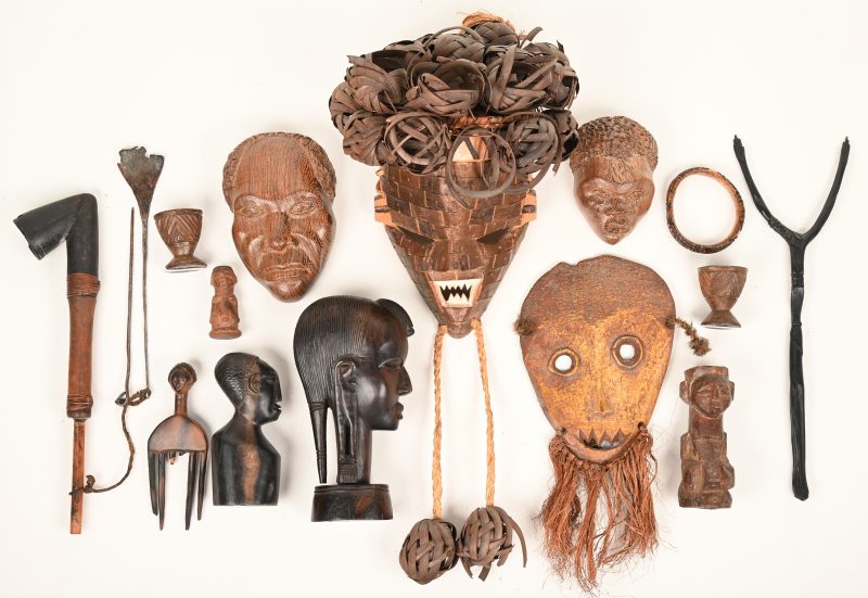 Een gevarieerd lot afrikaanse houten voorwerpen bestaande uit onder andere enkele maskers, een pijp, sculpturen van hoofden en twee eierdopjes.