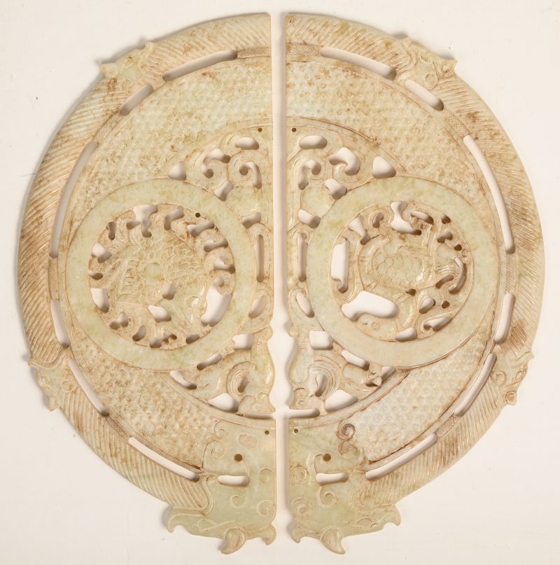 Een Chinese Bi-schijf in twee delen van gesculpteerd serpentijn, versierd met diverse dieren.
