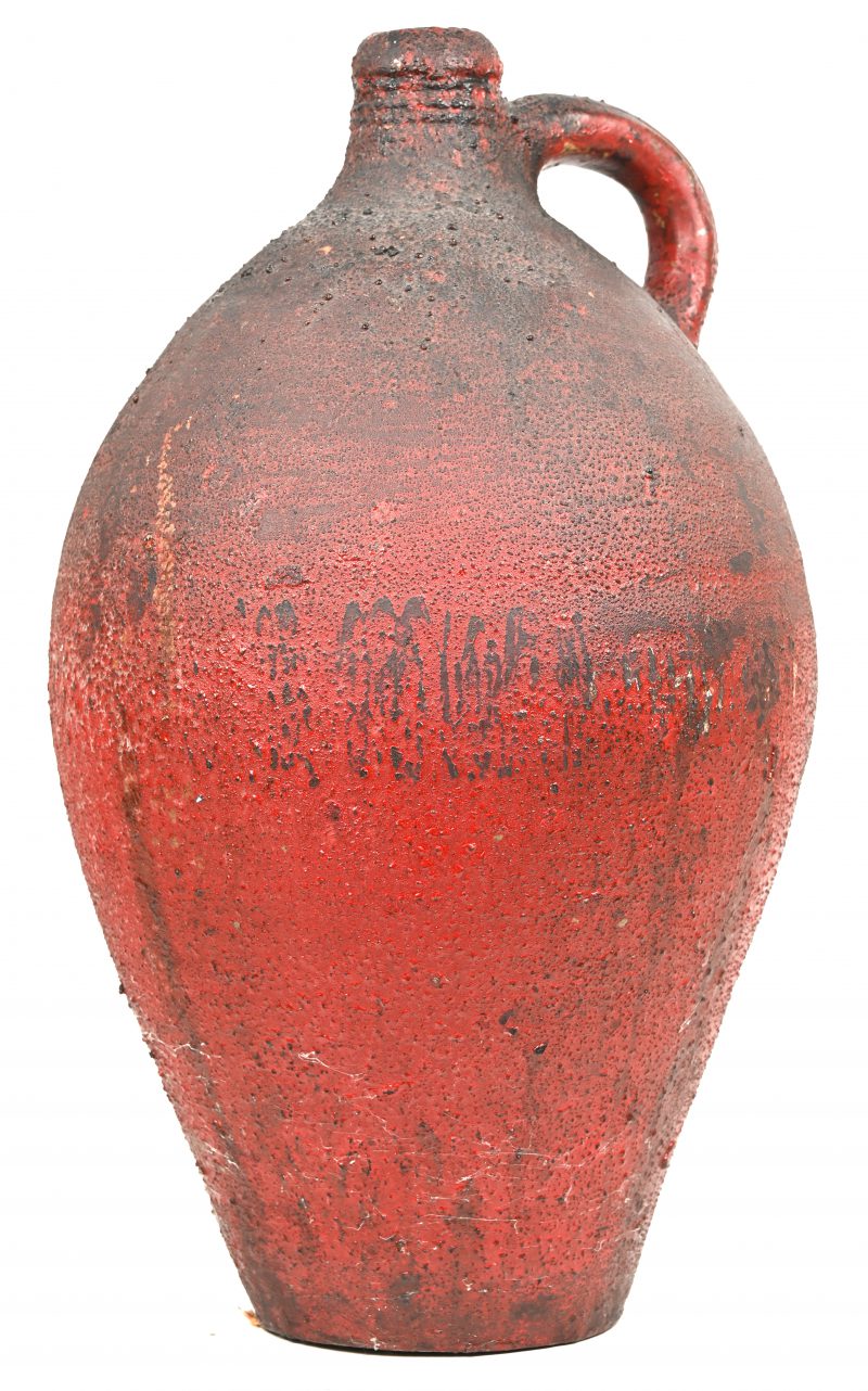 Een antieke kruik van rood geglazuurd steengoed.