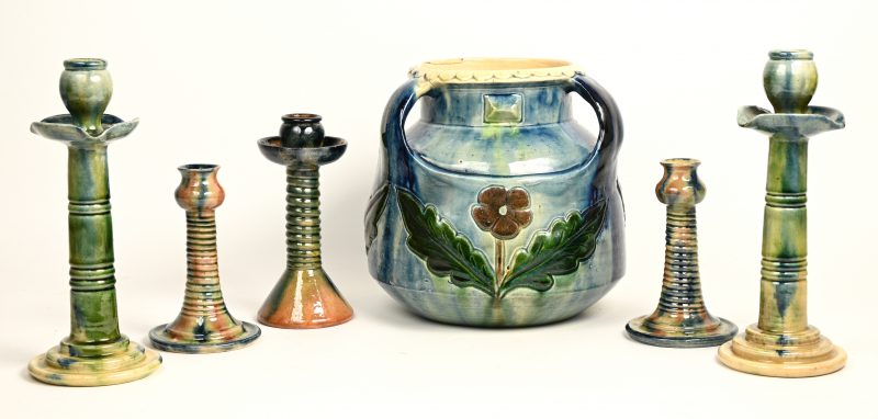 Een lot vlaams aardewerk bestaande uit vijf kandelaars en een pot met een bloemendecor in reliëf.