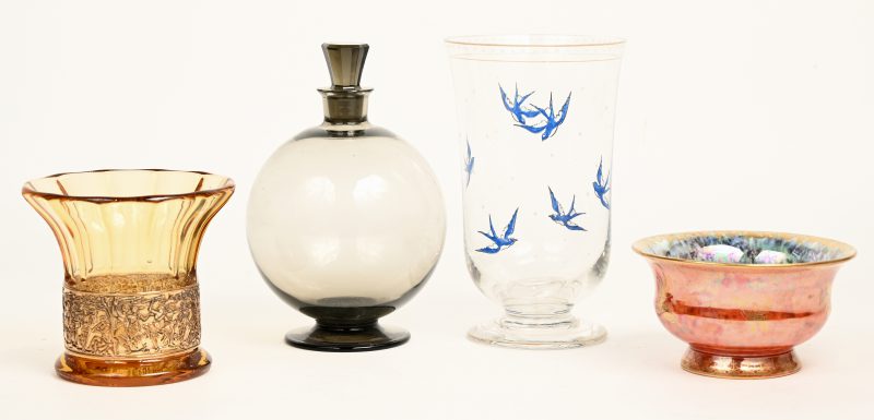 Een lotje van vier stuks glaswerk, bestaande uit een vaasje met handgeschilderde zwaluwen in het decor, een bol glazen karafje, een iriserend kommetje en een vaasje van amberkleurig glas, versierd met een fries.