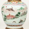 Een antieke vaas van Chinees porselein met decor van personages in rood, groen en bruin. Met fijn messingen voet en montuur.