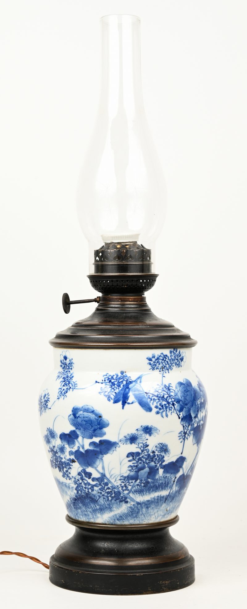Een olielamp met buik van Chinees porselein met blauw op wit decor. Gemonteerd op elektriciteit.
