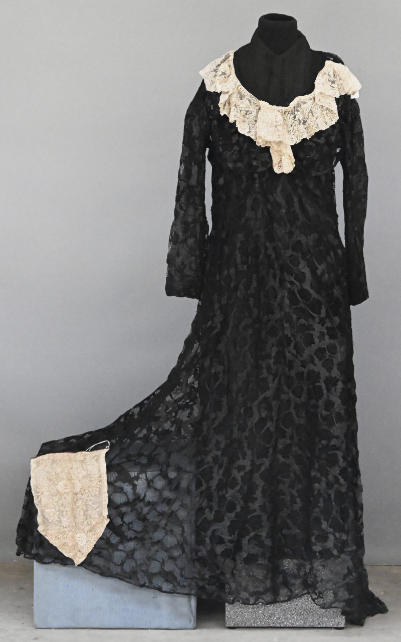 Een zwart kanten kleed met onderkleed bezet met een kraag van Rosaline perlé. We voegen er een bavette van 30 x 20 cm aan toe. Omstreeks 1900.