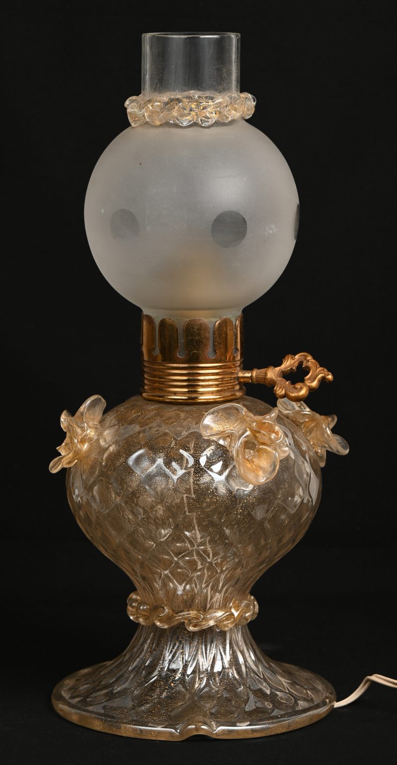 Een glazen olielamp, versierd met met de tang bewerkte bloempjes (één beschadigd). Aangepast op elektriciteit.