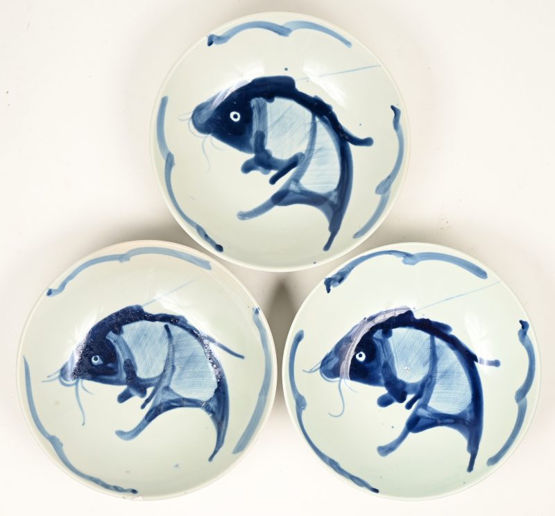 Drie diepe borden van Chinees porselein met een blauw op wit decor van een vis.