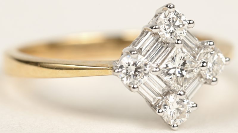 Een 18 K wit en geelgouden ring bezet met briljanten en diamanten baguetten met een gezamenlijk gewicht van +- 0,72 ct.