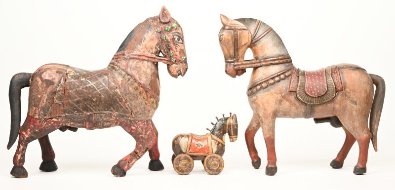 Drie houten paarden waarvan één op wielen. Indisch werk.
