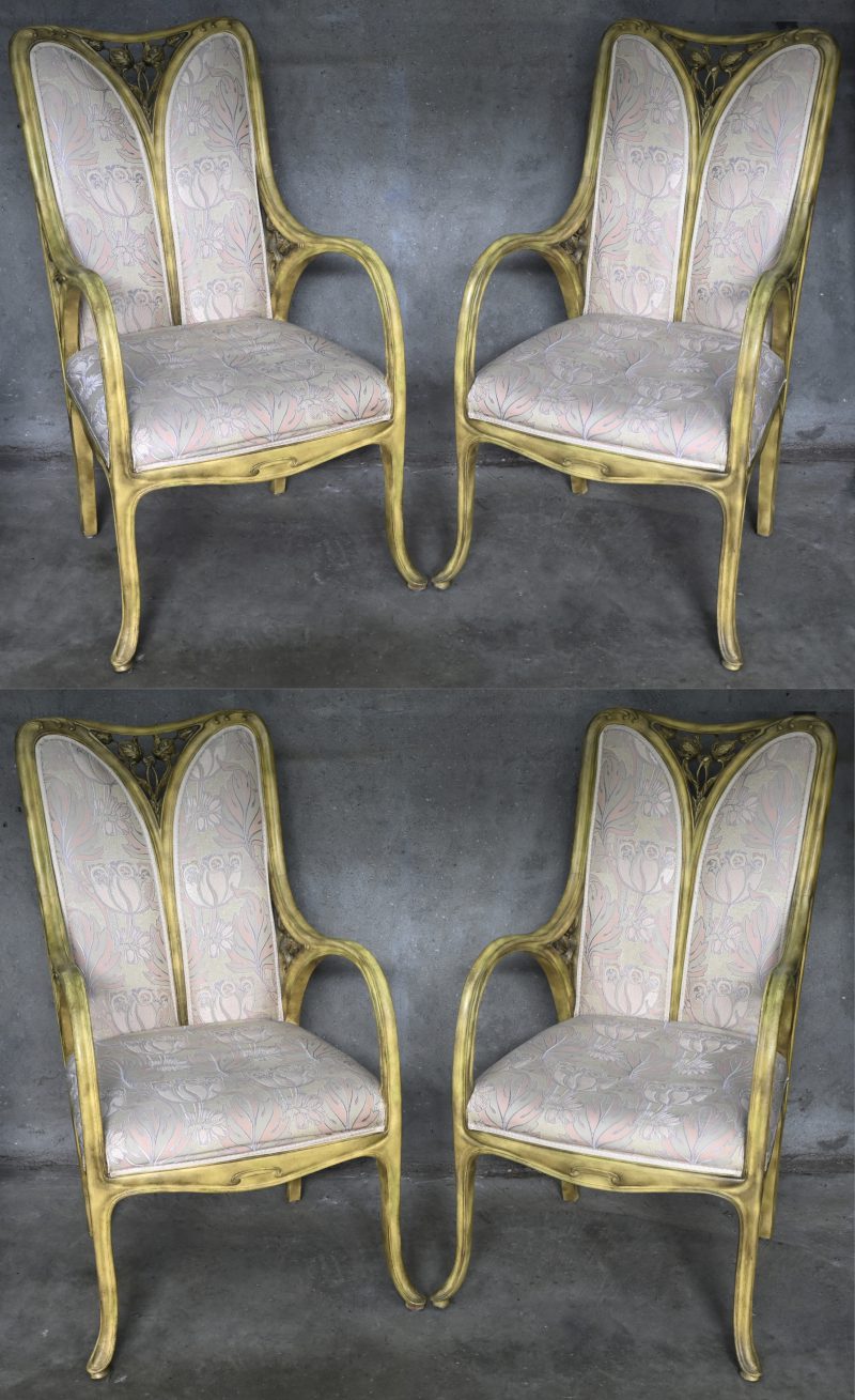Vier art nouveau stoelen met houtsnijwerk van bloemen in gebeitst hout en met stoffen bekleding versierd met takken.