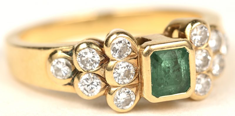 Een 18 K geelgouden ring bezet met briljanten met een gezamenlijk gewicht van +- 0,45 ct. en een centrale smaragd van +- 0,30ct.