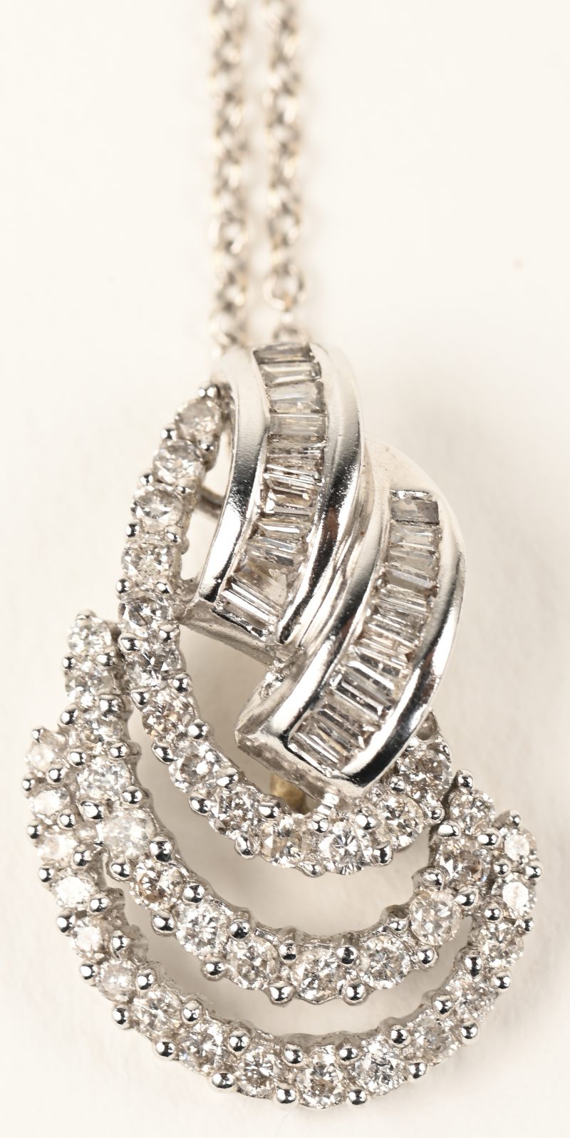 Een 18 K witgouden ketting met hanger bezet met diamanten en diamant baguetten een gezamenlijk gewicht van +- 0,80 ct.