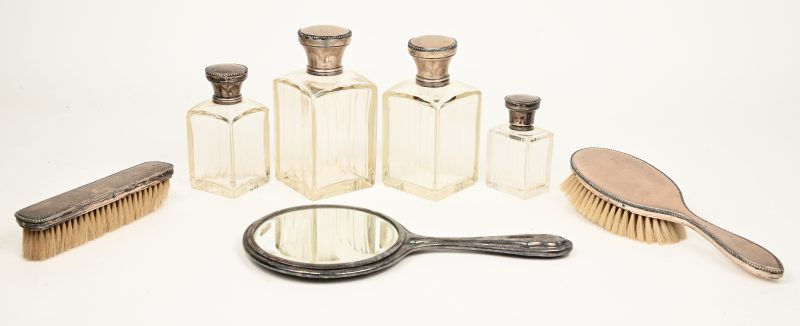 Een lot bestaande uit 4 flesjes, een spiegeltje en twee borstels met 800 ‰ zilveren montuurtjes.