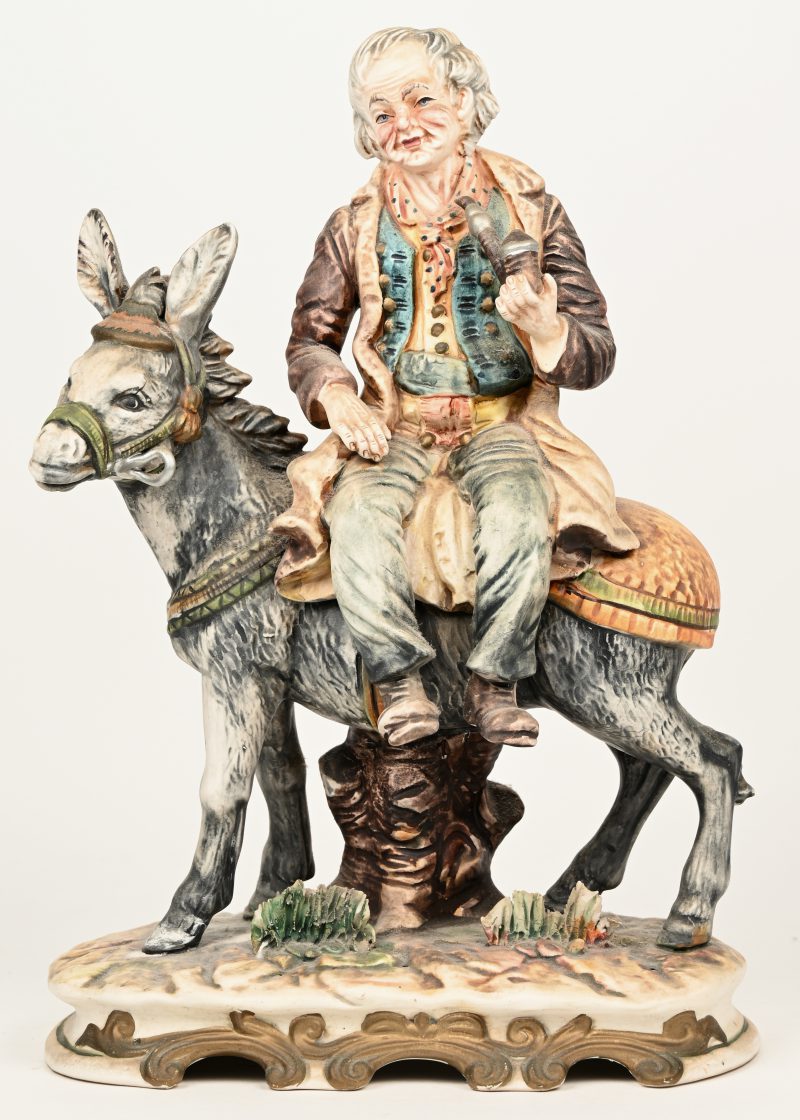 “Man met pijp op een ezel”. Een porseleinen beeldje van Capodimonte. Onderaan gemerkt.