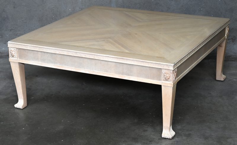 Een licht gepatineerd houten salontafel met leeuwenpoten en -kopjes.