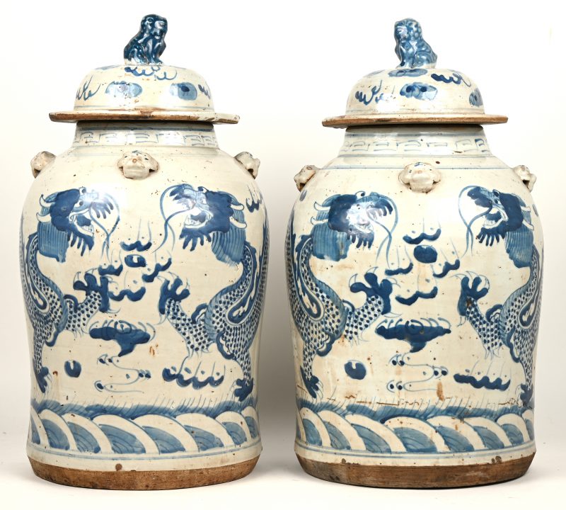 Een paar dekselpotten van chinees blauw en wit porselein versierd met tempelleuwen op de deksels.