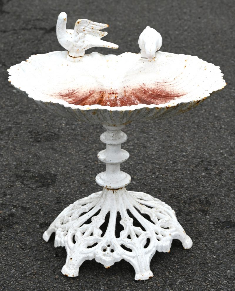 Een witgepatineerde gietijzeren vogelbadje versierd met drinkende vogels.