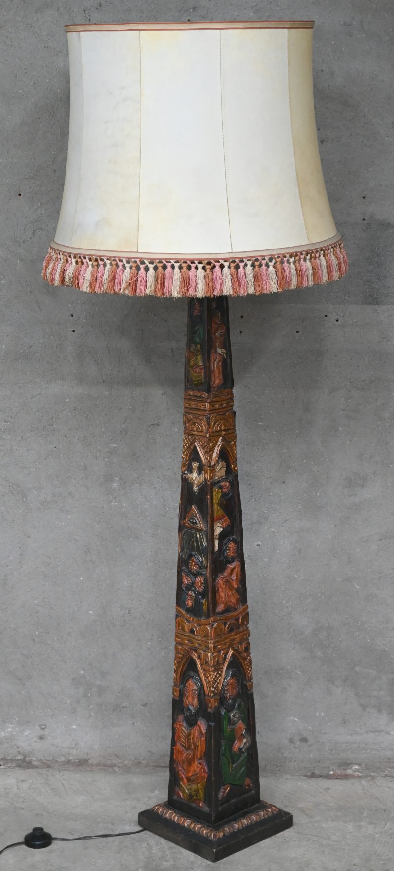 Een gebeeldhouwde en gepolychromeerde houten staande lamp met voorstellingen in vroegchristelijke stijl.