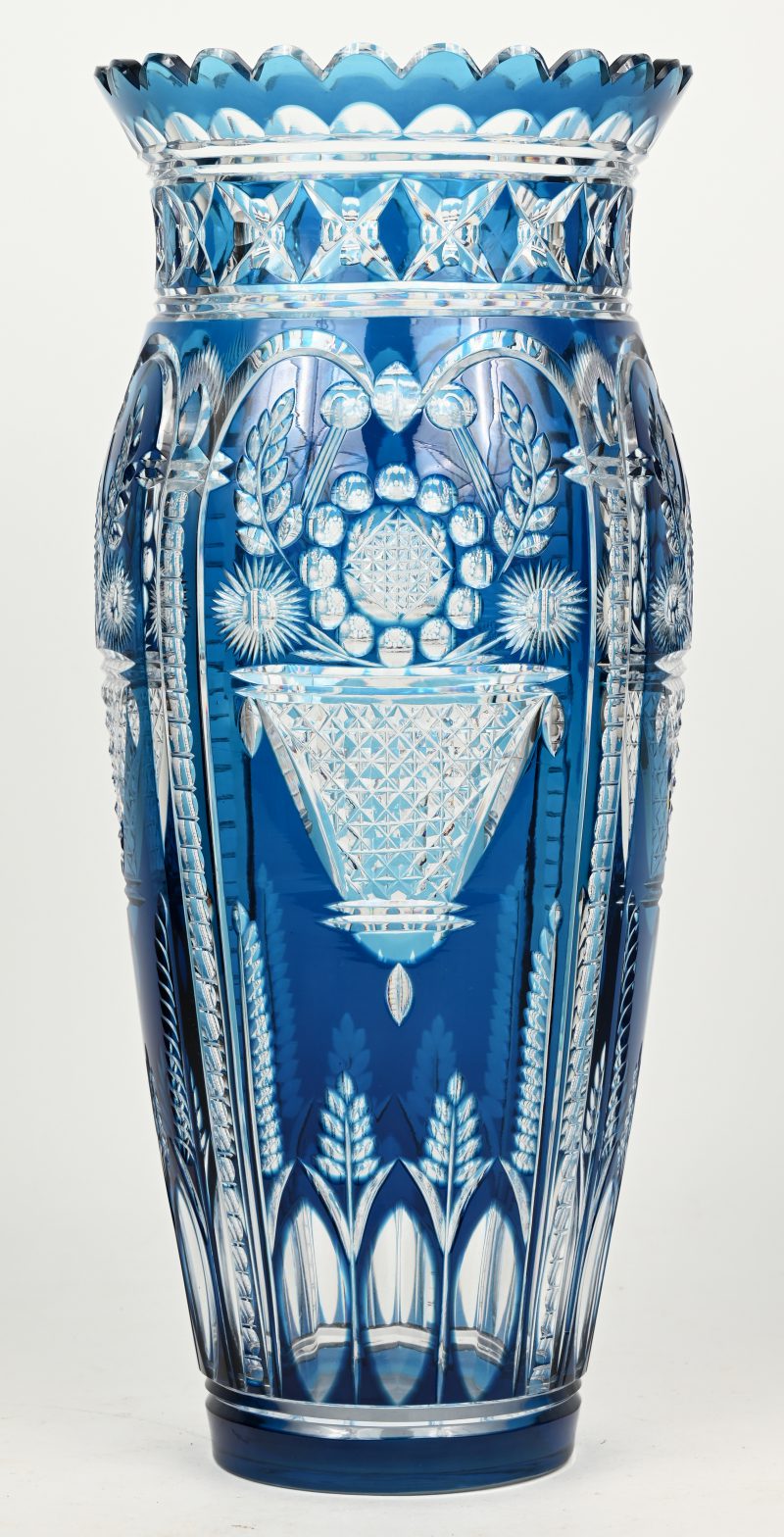 Een grote vaas van blauw gedubbeld kristal met geslepen decor van bloemenmanden en korenhalmen.
